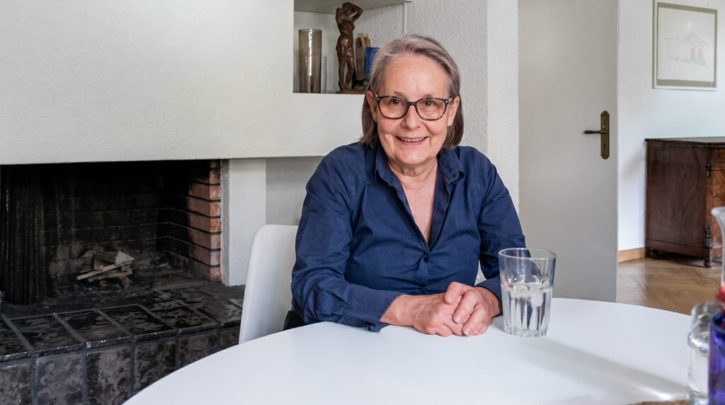 Frau Puorger sitzt lächelnd an ihrem Esstisch